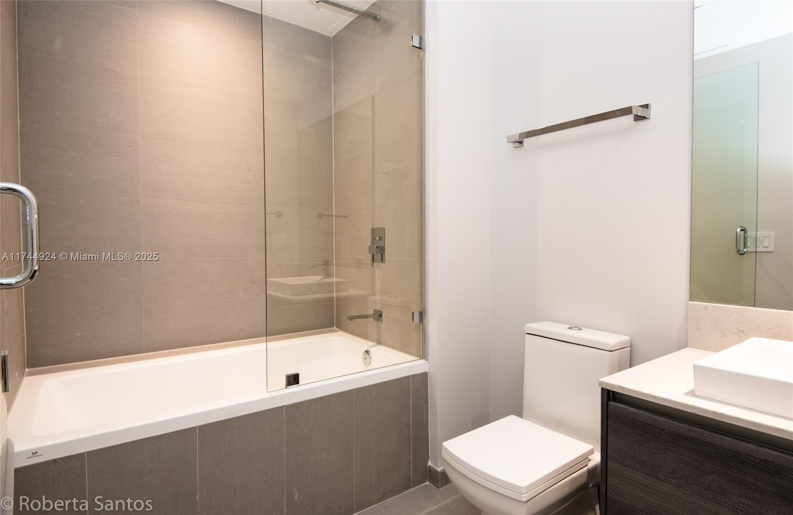 A modern bathroom features a glass-enclosed bathtub, a white toilet, and a vanity with a sink — 1080 Brickell Ave # 3205, Miami FL 33131, MIAMI, FL