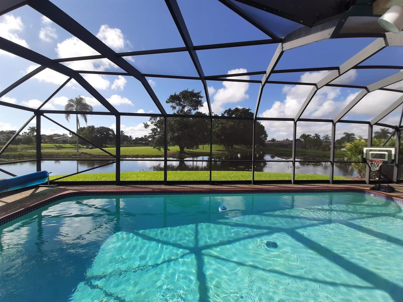 A swimming pool enclosed by a screened lanai overlooks a lake and golf course — 10544 Fenway Place, Boca Raton FL 33498, BOCA RATON, FL