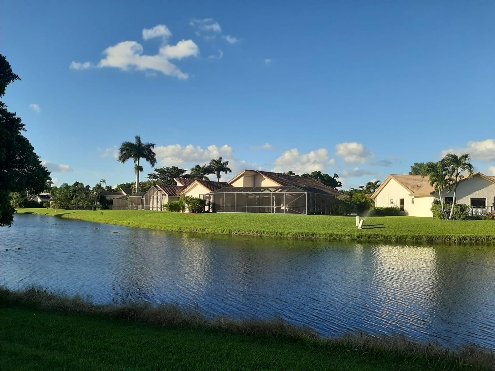 A view of several houses with screened-in lanais situated along a canal under a blue sky — 10544 Fenway Place, Boca Raton FL 33498, BOCA RATON, FL