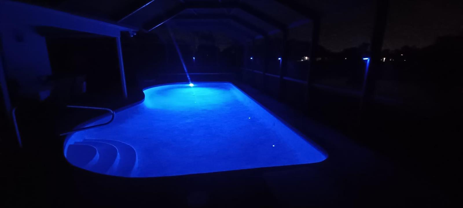 An illuminated swimming pool at night is enclosed within a screened-in lanai — 10544 Fenway Place, Boca Raton FL 33498, BOCA RATON, FL