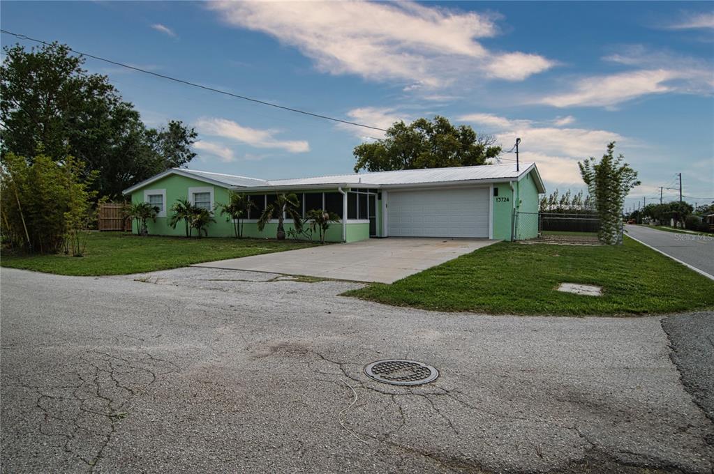 A light green, single-story house with a white roof and attached garage sits on a corner — 13724 COX AVENUE, HUDSON, FL
