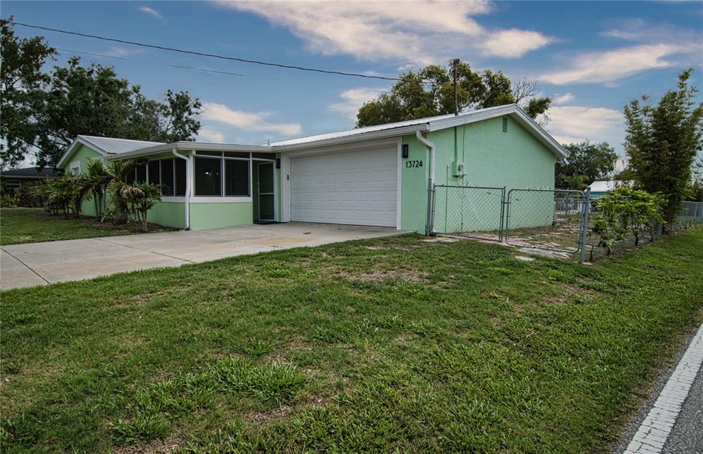 A light green house with a white garage door and a screened-in porch — 13724 COX AVENUE, HUDSON, FL