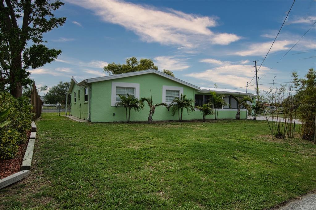 A light green, single-story house with a metal roof sits on a grassy lot — 13724 COX AVENUE, HUDSON, FL