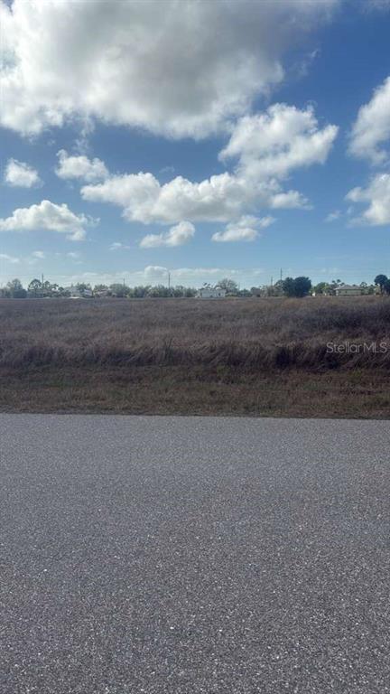A view of a vacant, grassy lot from an adjacent paved road under a blue sky — 53 LATEEN SAIL DRIVE, PLACIDA, FL