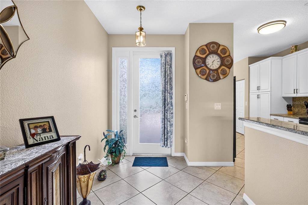 An entryway features tile flooring, a glass-paneled front door, and a wall-mounted decorative clock — 16141 AMETHYST KEY DRIVE, WIMAUMA, FL