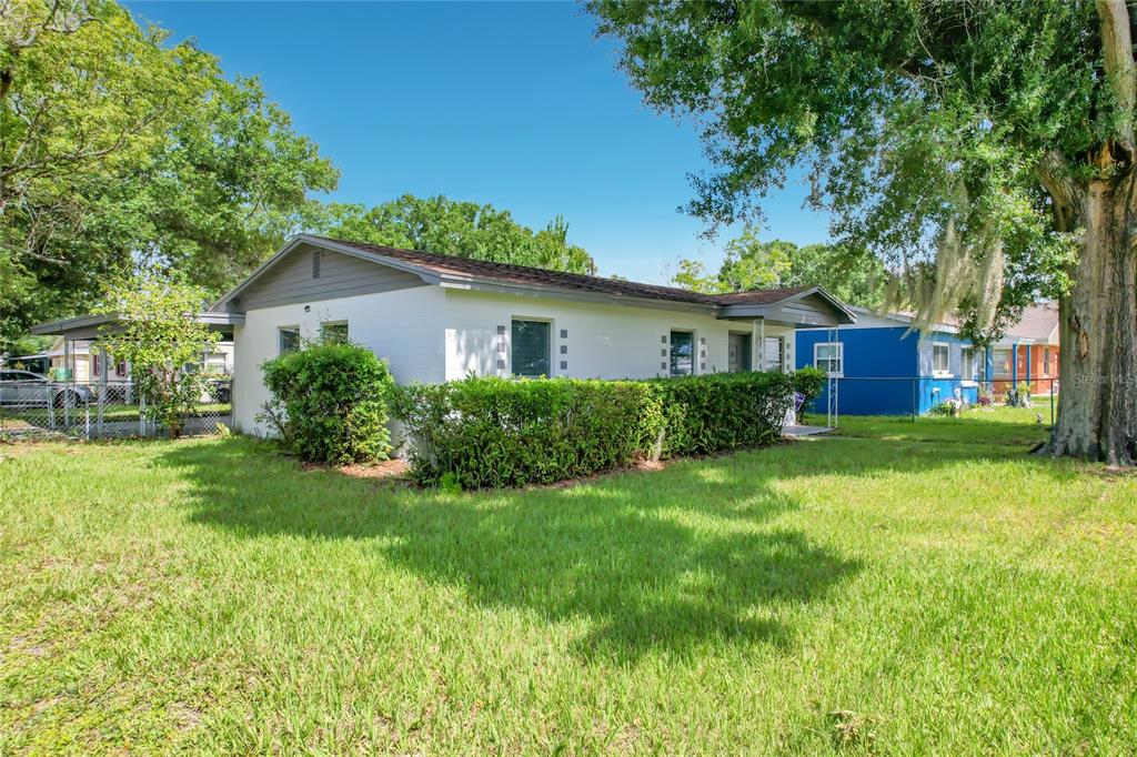 A white single-story house with a gray roof and a carport sits on a lawn — 1025 S CENTRAL AVENUE, LAKELAND, FL