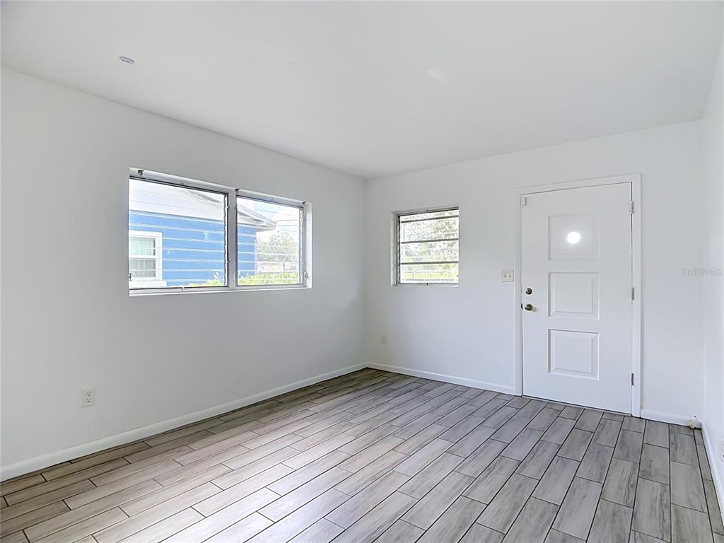 An empty room features white walls, gray wood-look tile flooring, and two windows — 1025 S CENTRAL AVENUE, LAKELAND, FL