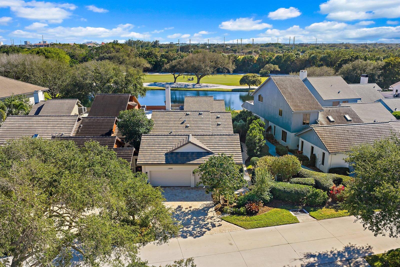 An aerial view shows a residential house with a tiled roof, garage, and backyard pond — 12092 SE Birkdale Run, Jupiter FL 33469, JUPITER, FL
