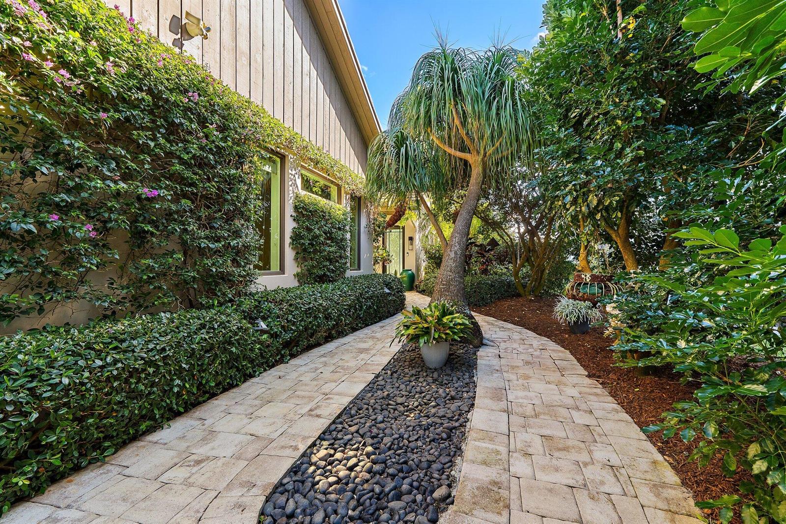 A stone paver walkway with a central rock bed leads toward a house exterior — 12092 SE Birkdale Run, Jupiter FL 33469, JUPITER, FL