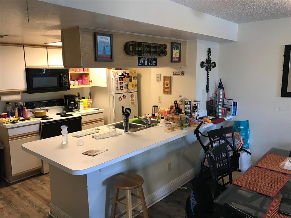 A kitchen features white countertops, wooden cabinets, a breakfast bar, and a dining area — 2468 SWEETWATER CLUB CIRCLE UNIT 111, KISSIMMEE, FL