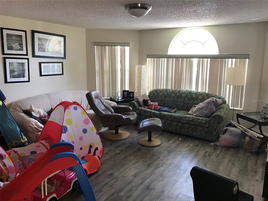 A living room features wood-look flooring, two sofas, a recliner, and a child's play tent — 2468 SWEETWATER CLUB CIRCLE UNIT 111, KISSIMMEE, FL