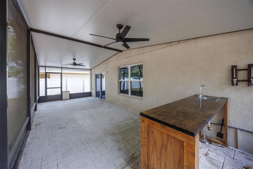 A kitchen features dark wood cabinets, gray laminate countertops, stainless steel appliances, and tile flooring — 5461 MAGDALENE WAY, ZEPHYRHILLS, FL