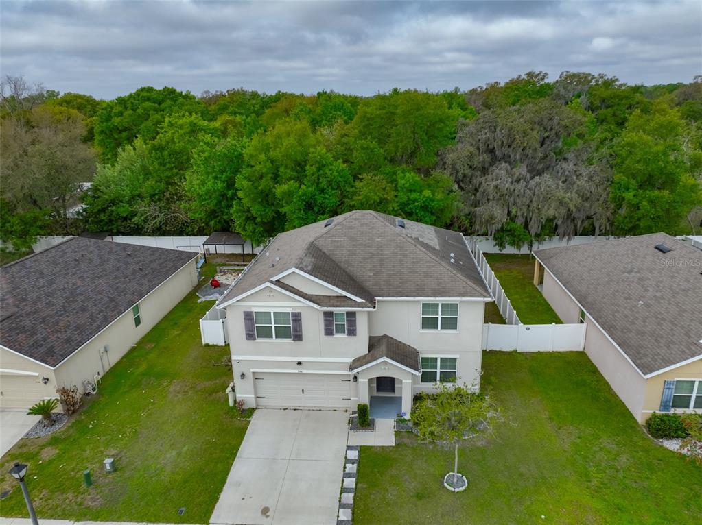 A backyard features a screened-in patio, a stone fire pit, and a white privacy fence — 5461 MAGDALENE WAY, ZEPHYRHILLS, FL