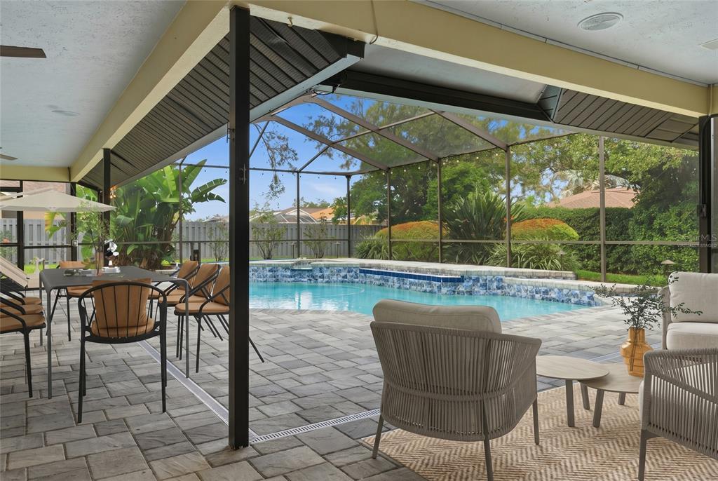 A covered patio with outdoor furniture overlooks a swimming pool enclosed by a screen cage — 3612 SUGAR LOAF LANE, VALRICO, FL