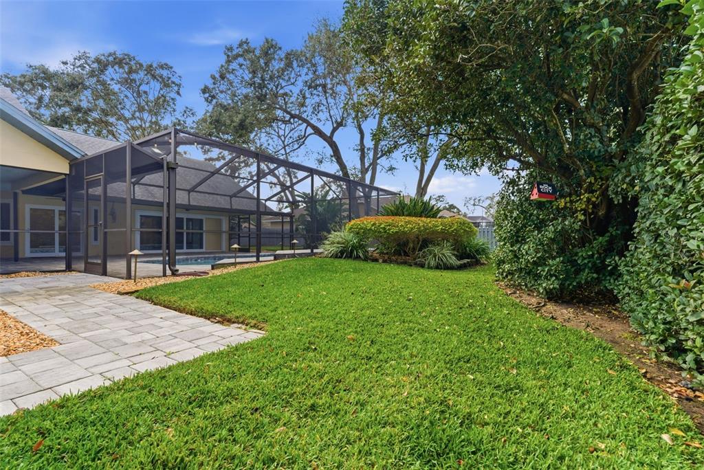A backyard features a screened-in pool enclosure, a paved patio, and a manicured lawn — 3612 SUGAR LOAF LANE, VALRICO, FL