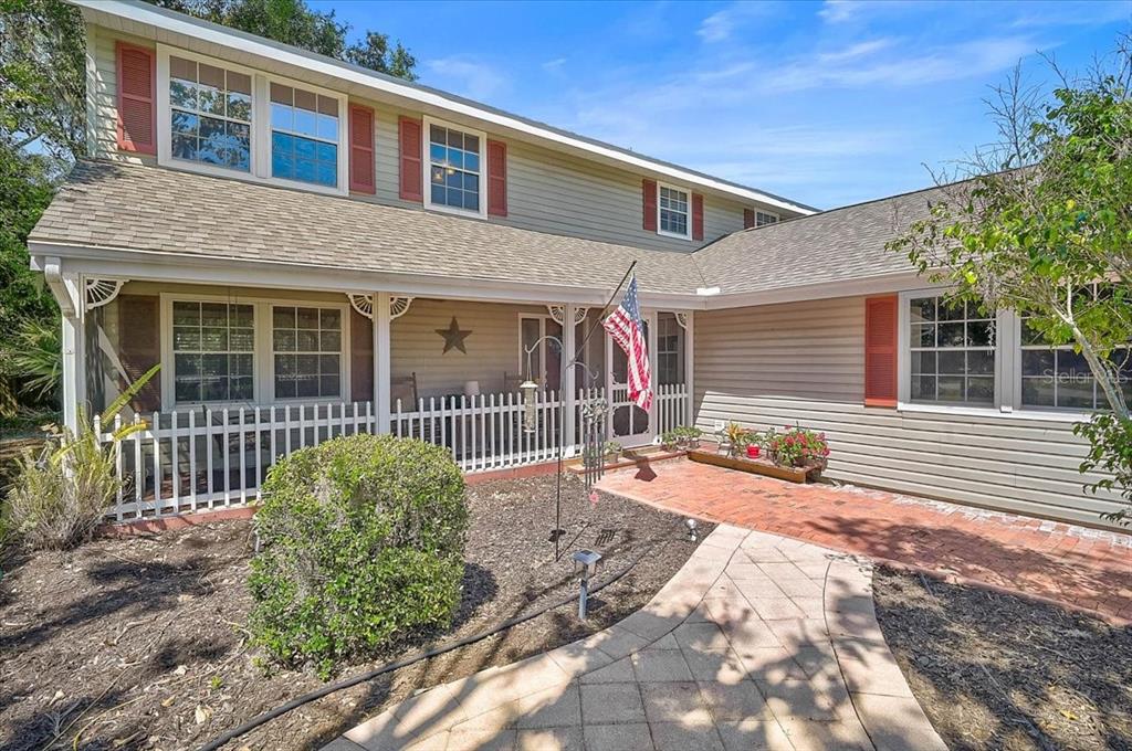 A two-story house with light siding, red shutters, a front porch, and a brick walkway — 3328 TOBERO LANE, SARASOTA, FL