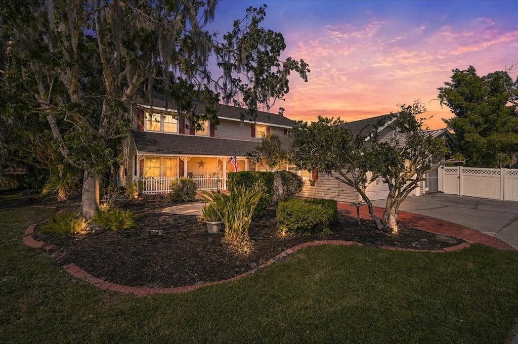 A two-story house with a front porch, landscaping, and a driveway at sunset — 3328 TOBERO LANE, SARASOTA, FL