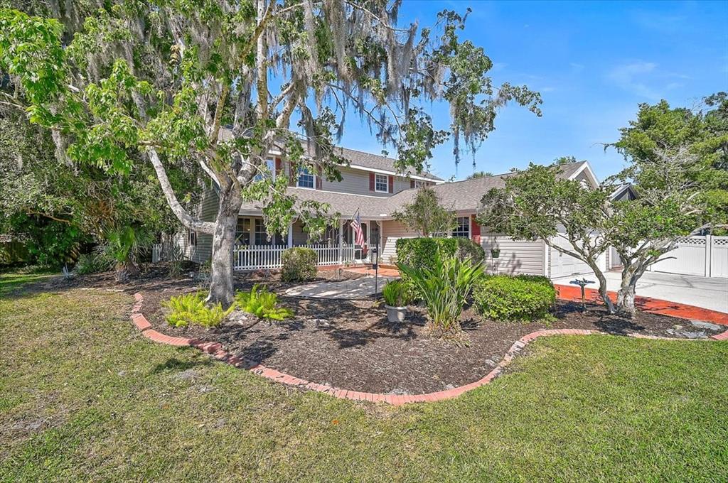 A two-story house with a front porch, landscaping, and a large tree with Spanish moss — 3328 TOBERO LANE, SARASOTA, FL