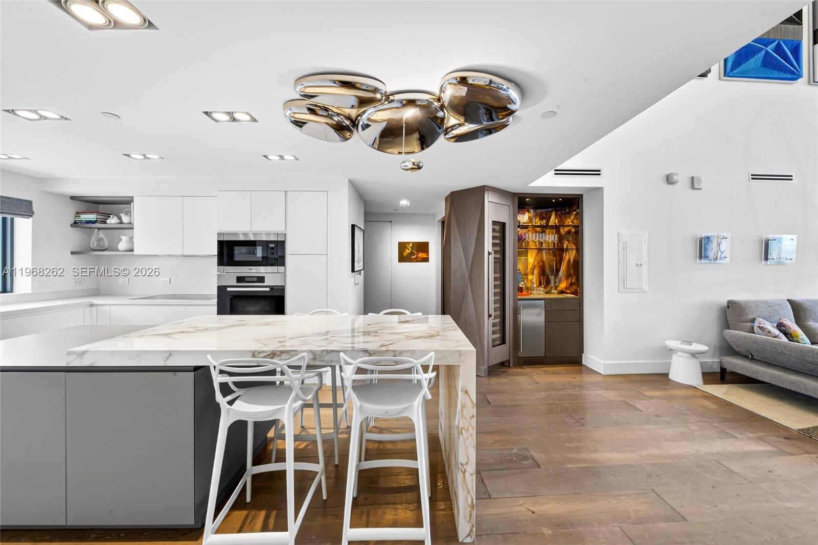 A modern kitchen features a marble-topped island, white cabinetry, and a built-in wine bar — 601 NE 36th St # 3407, Miami FL 33137, MIAMI, FL