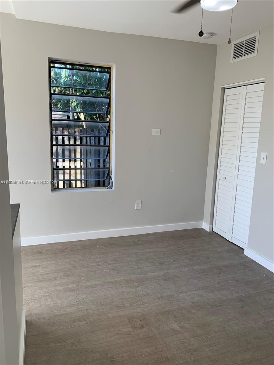 A bedroom features light gray walls, wood-look flooring, a jalousie window, and a white closet — 2932 NW 16th Ave # 2B, Miami FL 33142, MIAMI, FL