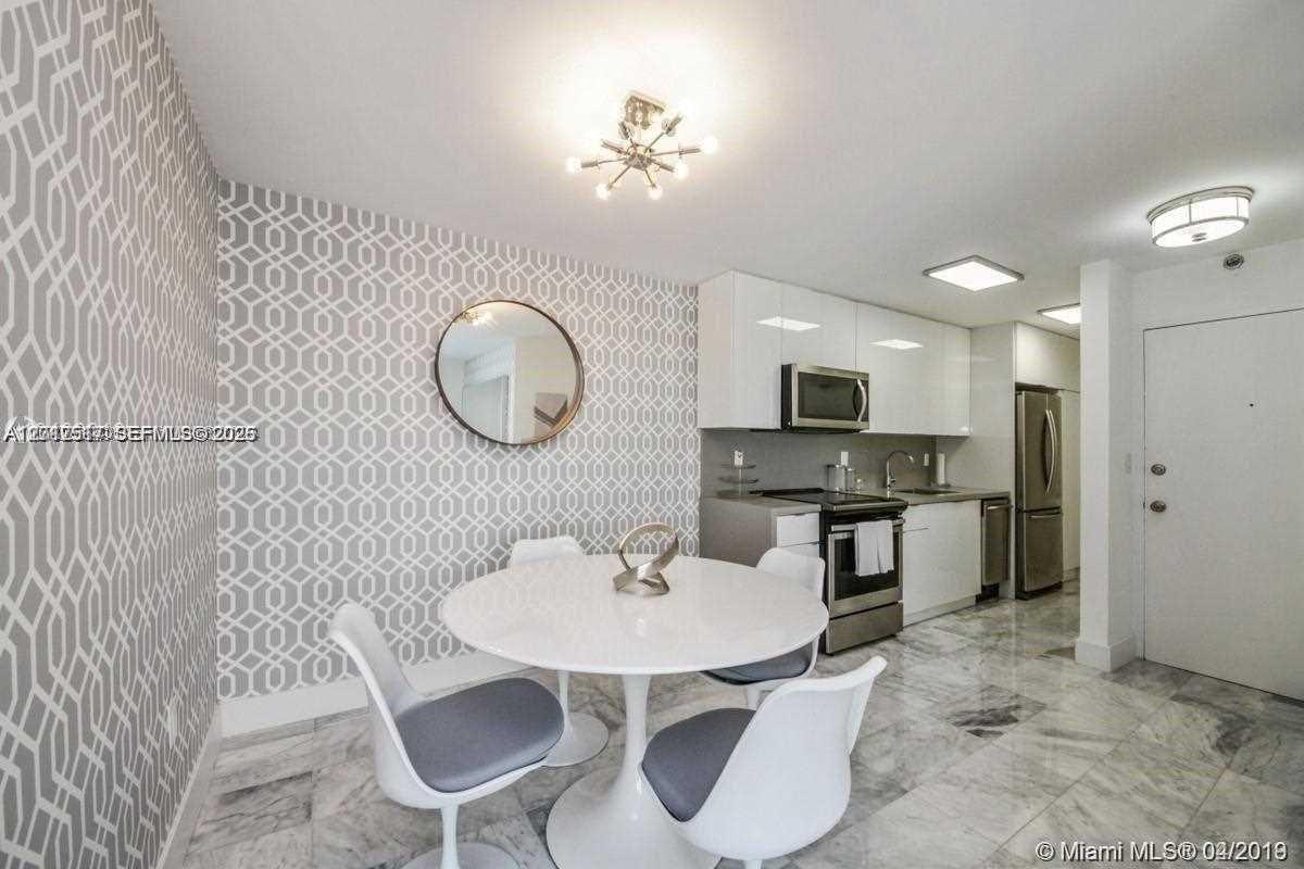 A dining area with patterned wallpaper and a round table sits adjacent to a kitchen — 1255 Collins Ave # 507, Miami Beach FL 33139, MIAMI BEACH, FL