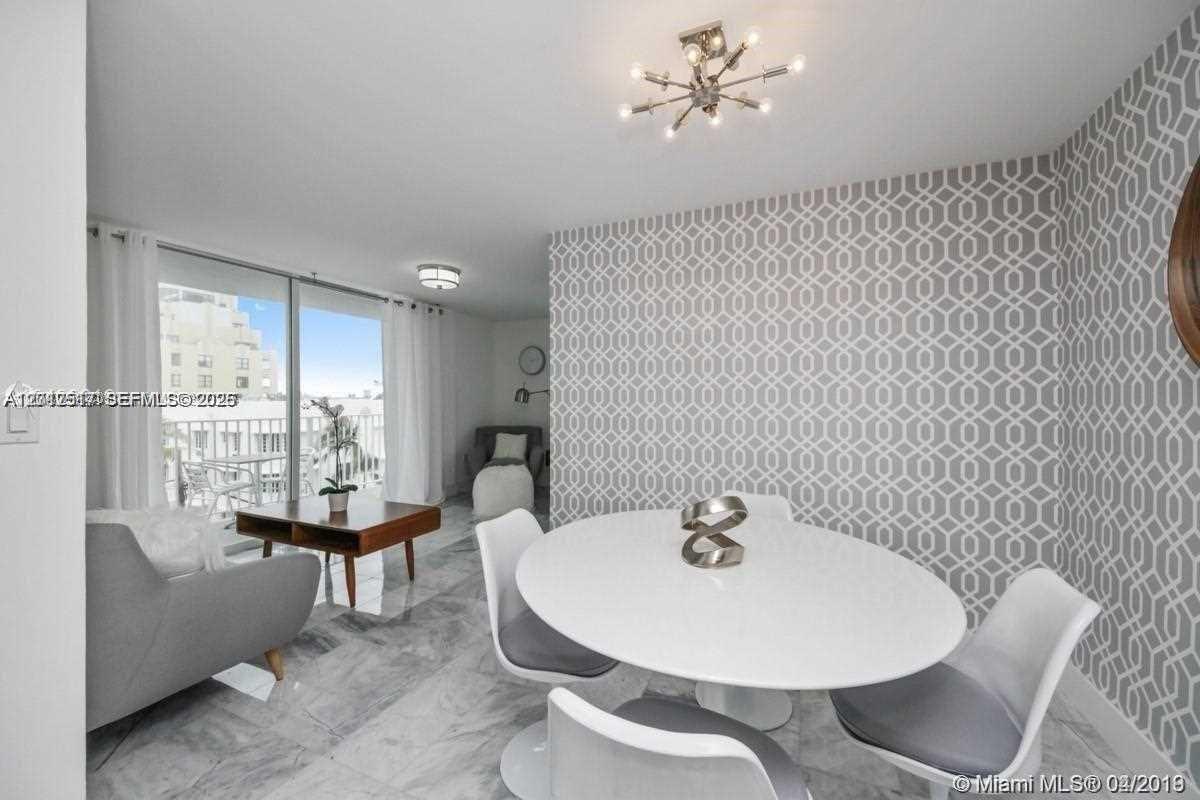A dining area with a patterned accent wall, white table, and marble flooring — 1255 Collins Ave # 507, Miami Beach FL 33139, MIAMI BEACH, FL