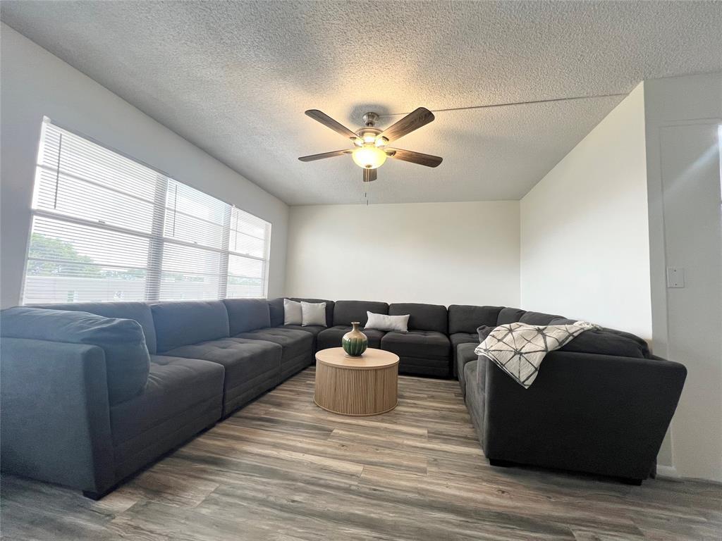 A living room features a large gray sectional sofa, a round coffee table, and flooring — 410 Grantham A # 410, Deerfield Beach FL 33442, DEERFIELD BEACH, FL