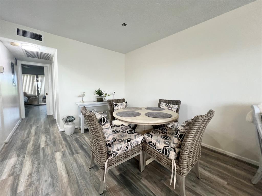 A dining area features a round table with four wicker chairs on wood-look flooring — 410 Grantham A # 410, Deerfield Beach FL 33442, DEERFIELD BEACH, FL