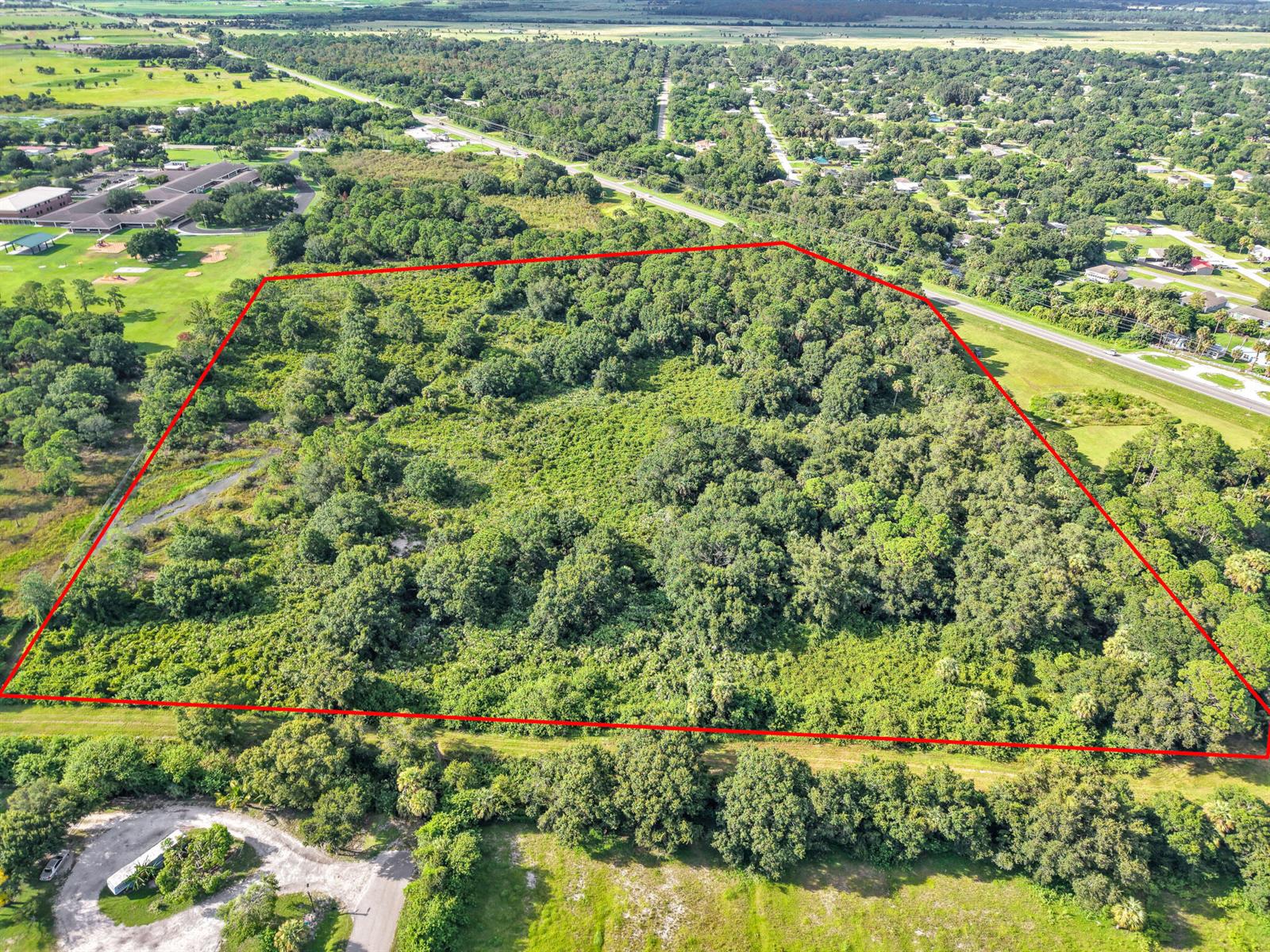 An aerial view shows a large, rectangular plot of wooded land outlined in red — 100 NW 38th Avenue, Okeechobee FL 34972, OKEECHOBEE, FL