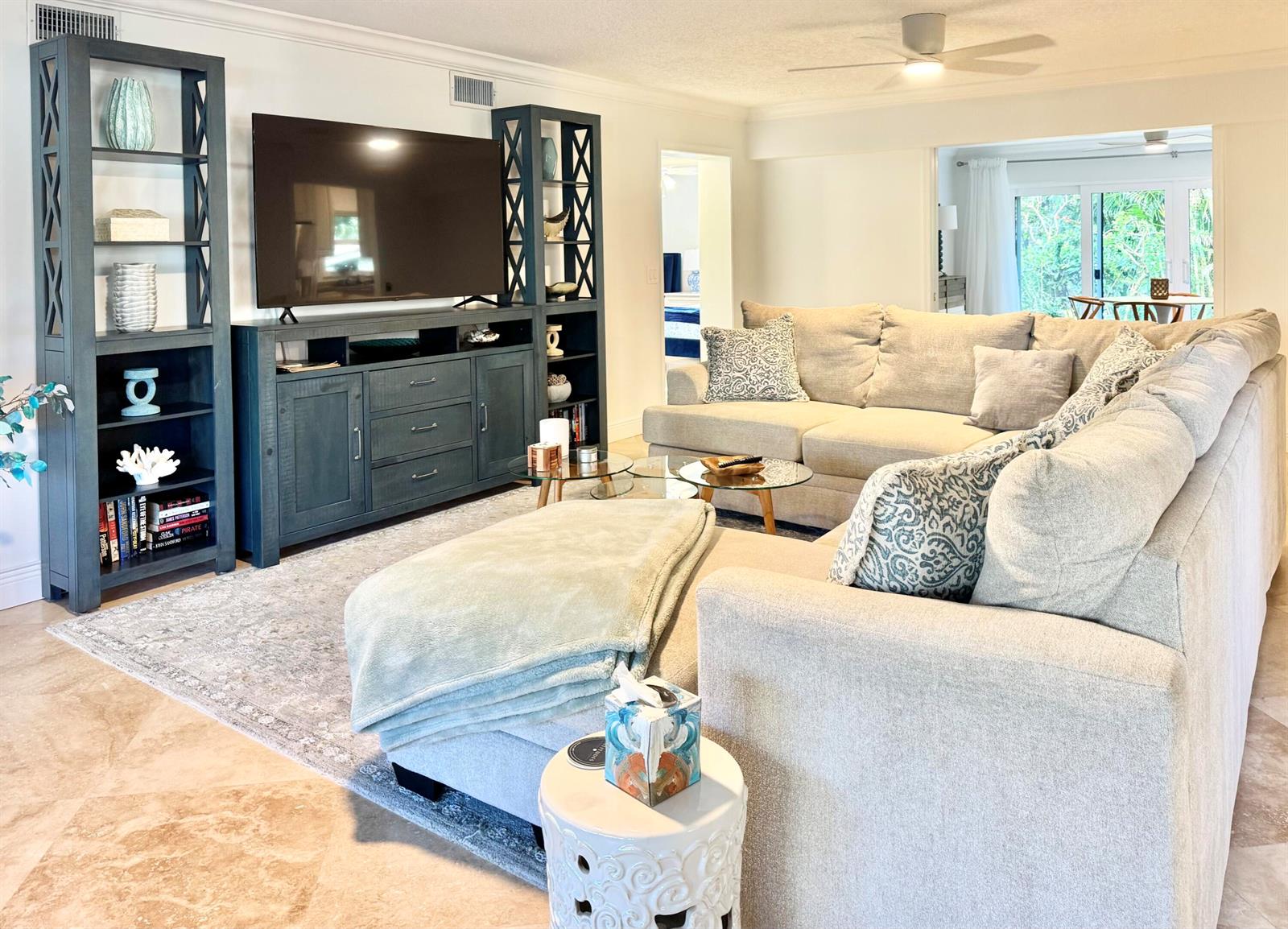 A living room features a large sectional sofa, a television console, and matching shelving units — 4161 U.s. Hwy 1 # I2, Jupiter FL 33477, JUPITER, FL