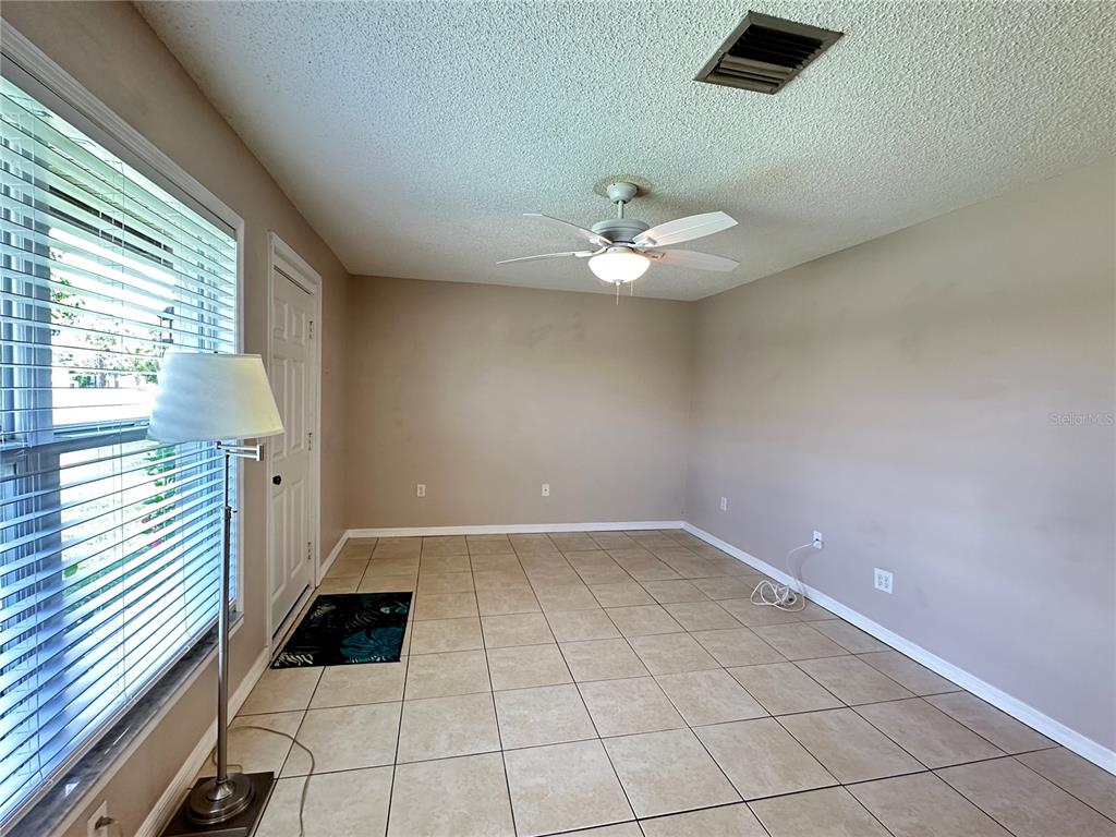 An empty room features beige tile flooring, a ceiling fan, and a window with blinds — 21150 GERTRUDE AVENUE UNIT N3, PORT CHARLOTTE, FL