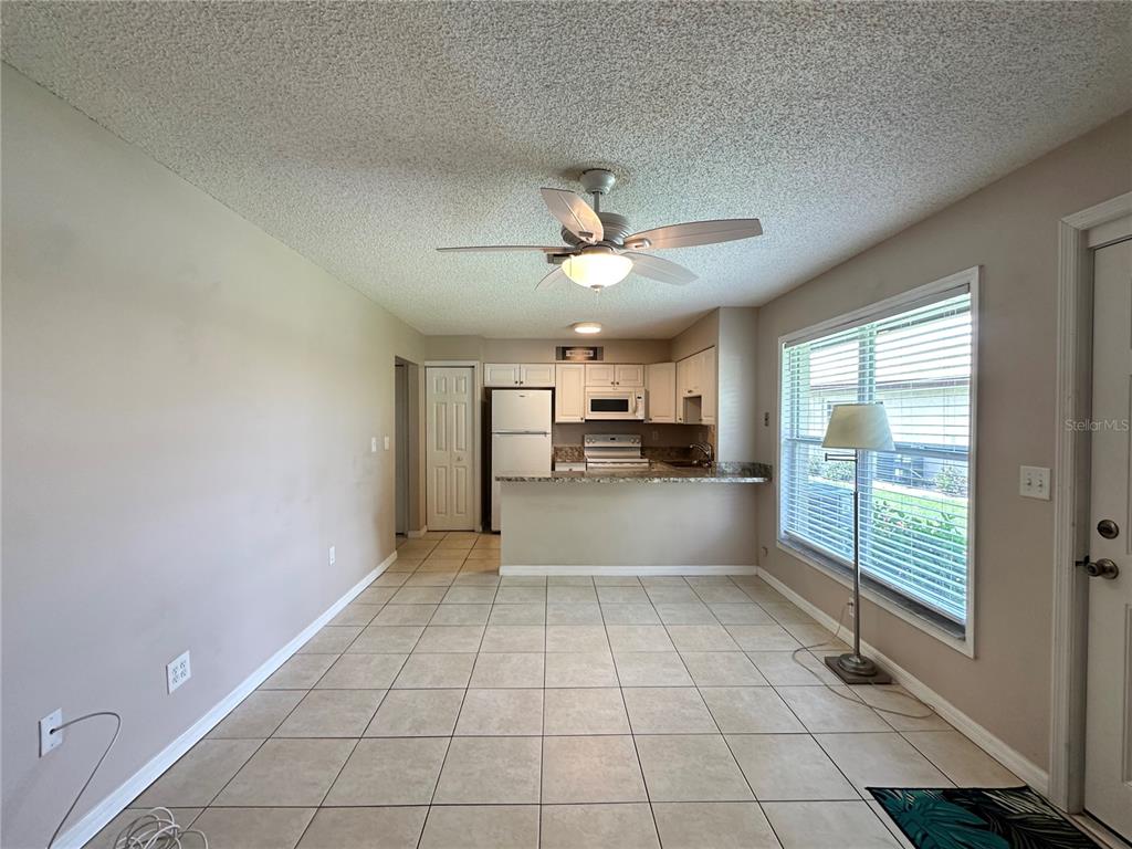 An open-concept kitchen and dining area features tile flooring, a ceiling fan, and white cabinetry — 21150 GERTRUDE AVENUE UNIT N3, PORT CHARLOTTE, FL
