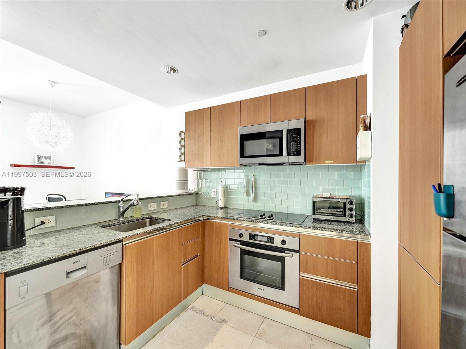 A kitchen features light wood cabinets, stainless steel appliances, and a light green subway tile backsplash — 1050 Brickell Ave # 2722, Miami FL 33131, MIAMI, FL