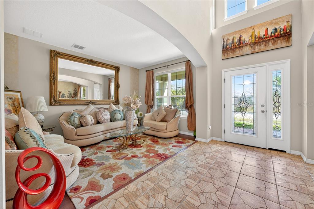 A living room with tile flooring, a large area rug, and a front entryway door — 882 COUNTS CREST CIRCLE, APOPKA, FL