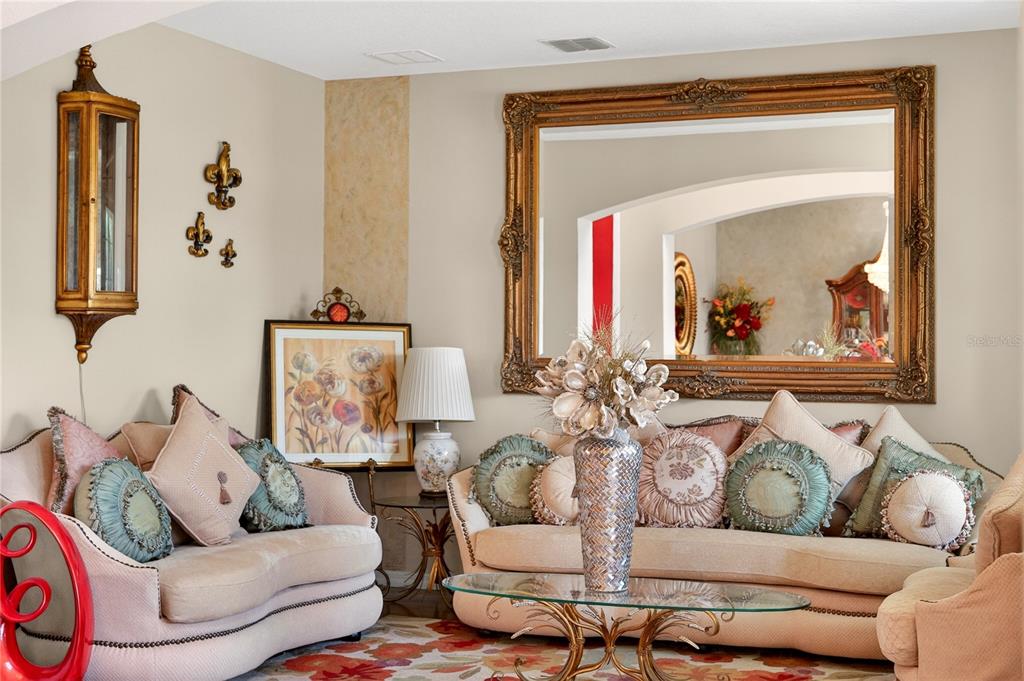 A living room features two beige sofas, a glass coffee table, and a large ornate mirror — 882 COUNTS CREST CIRCLE, APOPKA, FL
