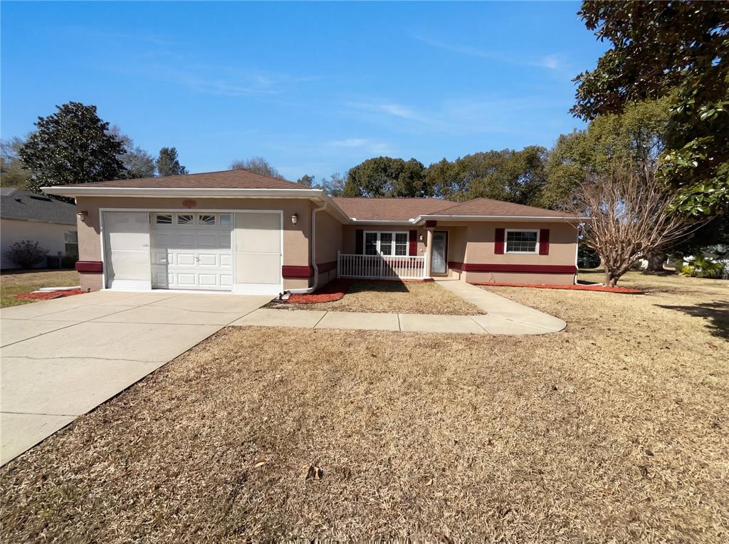 A single-story house with a tan exterior, red trim, and a white garage door — 13824 SW 114TH CIRCLE, DUNNELLON, FL