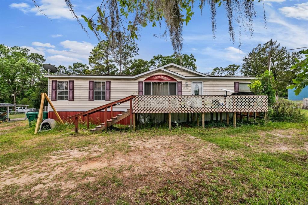 A single-story manufactured home features a raised wooden deck with lattice skirting and stairs — 5074 N DEWEY WAY, HERNANDO, FL