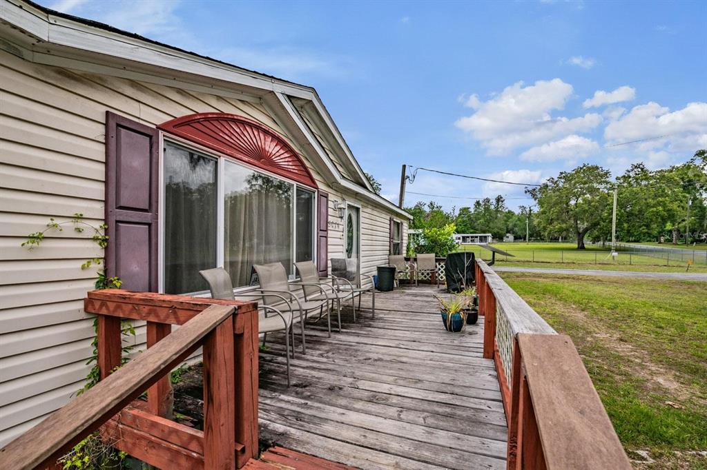 A wooden deck with chairs runs along the side of a beige mobile home — 5074 N DEWEY WAY, HERNANDO, FL