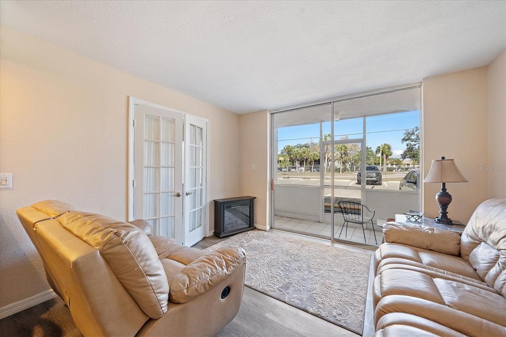 A living room features two leather sofas, a rug, French doors, and a screened balcony — 519 ALBEE FARM ROAD UNIT 111, VENICE, FL