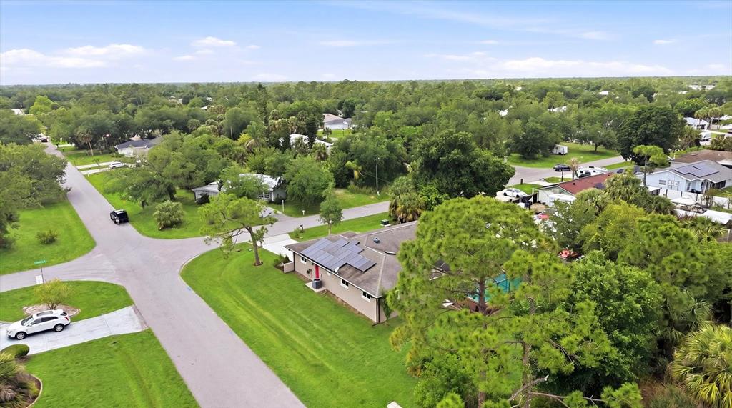 An aerial view shows a house with solar panels on its roof in a neighborhood — 1114 DEWHURST STREET, PORT CHARLOTTE, FL