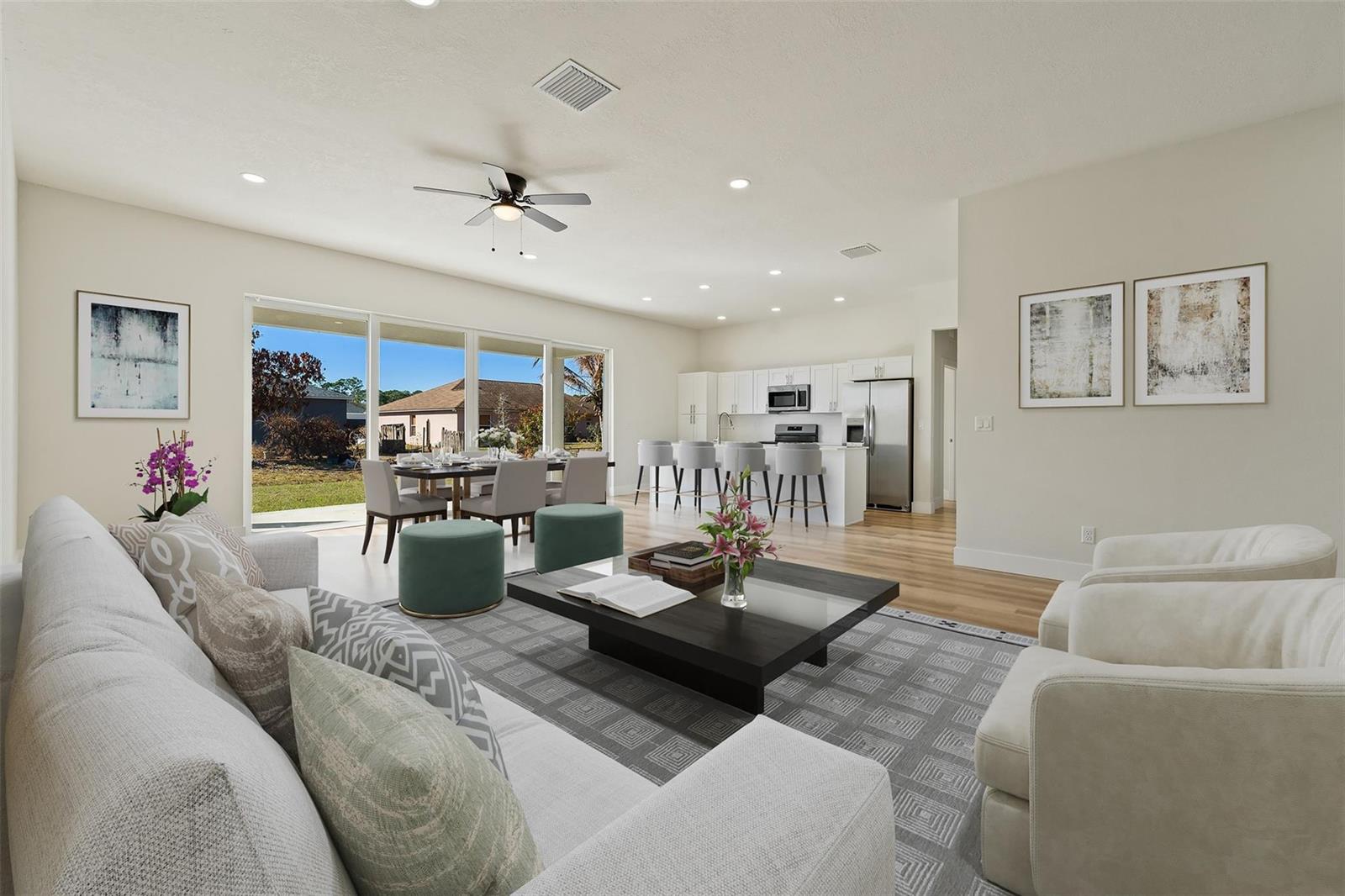 An open-concept living and dining area features a modern kitchen, light flooring, and large windows — 774 Cleaves Street, Palm Bay FL 32909, PALM BAY, FL