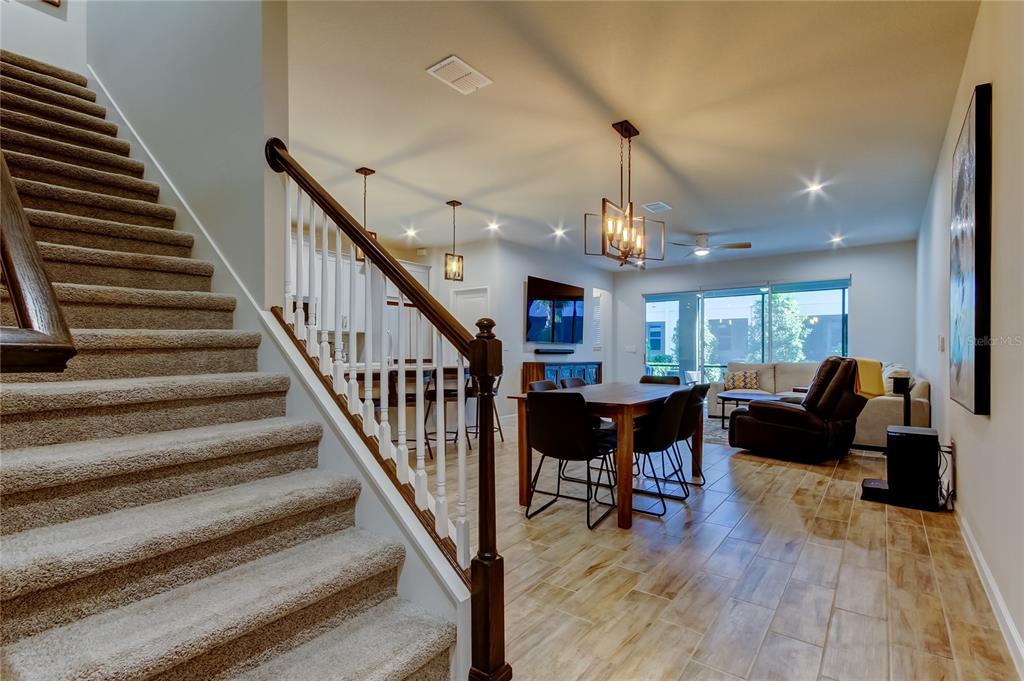 A kitchen features a white island with bar stools, gray cabinetry, and stainless steel appliances — 19388 GREAT INTENTION WAY, LUTZ, FL