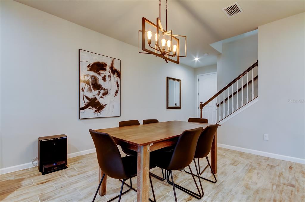 An open-concept kitchen and dining area features light gray cabinets, wood-look tile floors, and pendant lighting — 19388 GREAT INTENTION WAY, LUTZ, FL