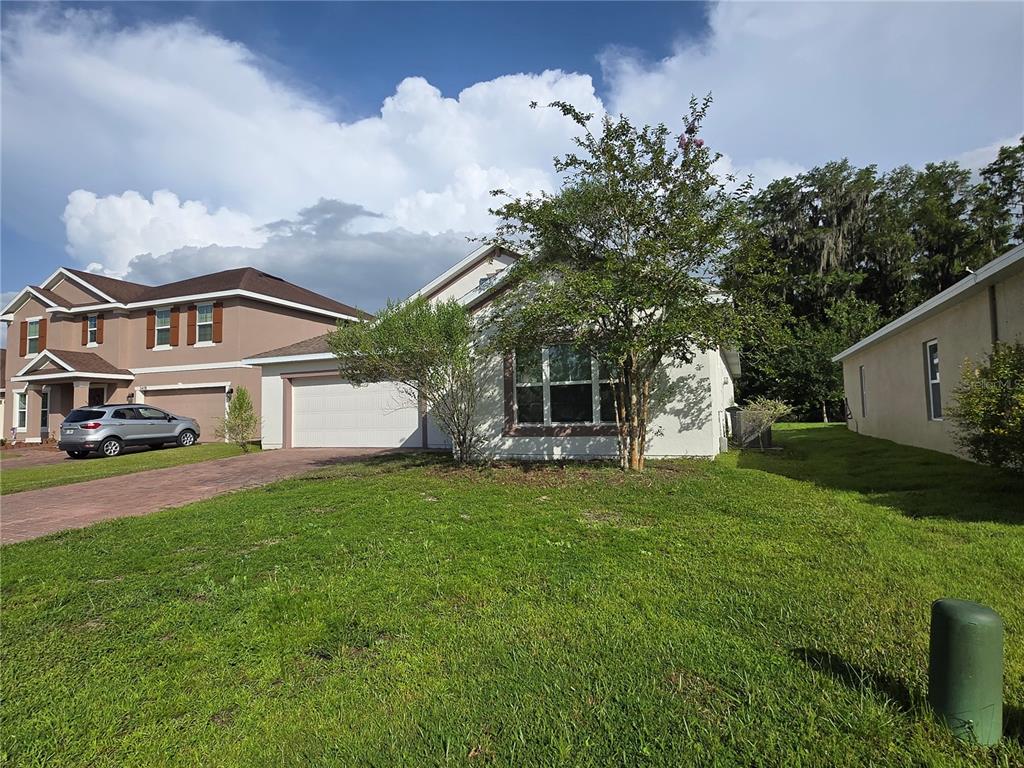 A single-story house with a white exterior, a two-car garage, and a front yard — 2476 ADDISON CREEK DRIVE, KISSIMMEE, FL