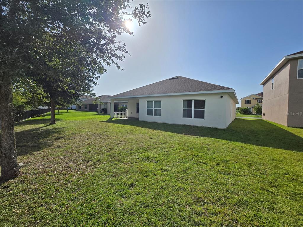 The exterior rear view of a single-story house with a lawn and patio — 2476 ADDISON CREEK DRIVE, KISSIMMEE, FL
