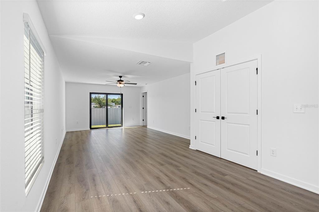 An empty room with white walls, wood-look flooring, a ceiling fan, and double closet doors — 15306 SCAUP DUCK ROAD, WEEKI WACHEE, FL