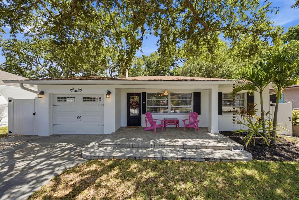 A white single-story house with a paved front porch, two pink chairs, and a garage — 1023 GRANADA STREET, CLEARWATER, FL