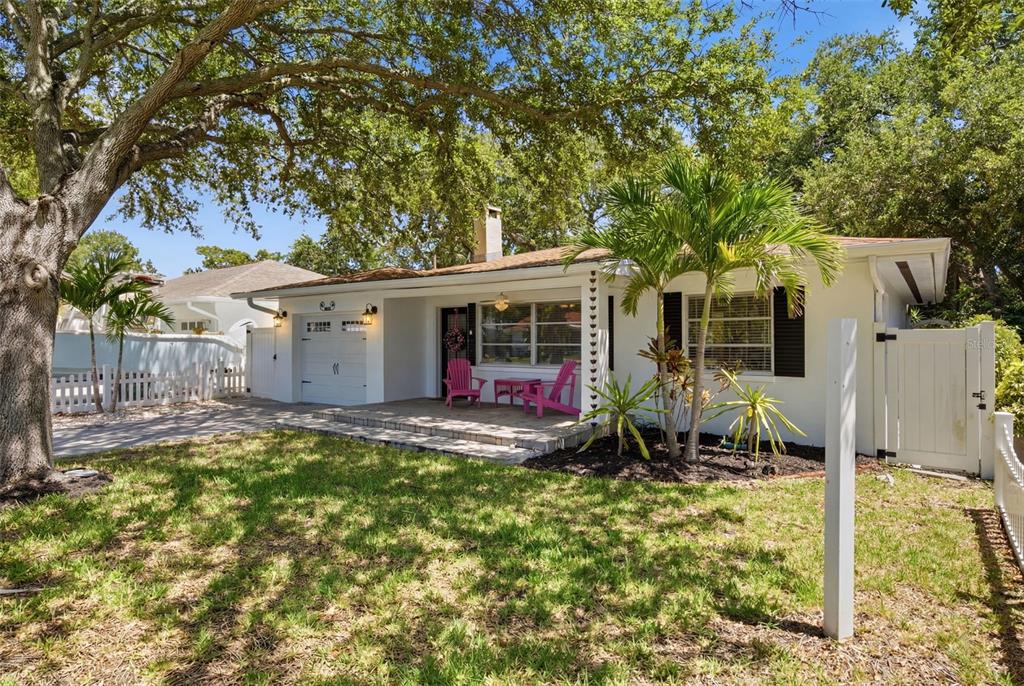 A white single-story house with a front porch, palm trees, and a large oak tree — 1023 GRANADA STREET, CLEARWATER, FL