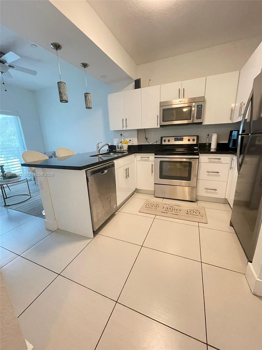 A modern kitchen features white cabinets, stainless steel appliances, and a black countertop island — 106 SE 9th Ct # 201, Hallandale Beach FL 33009, HALLANDALE BEACH, FL