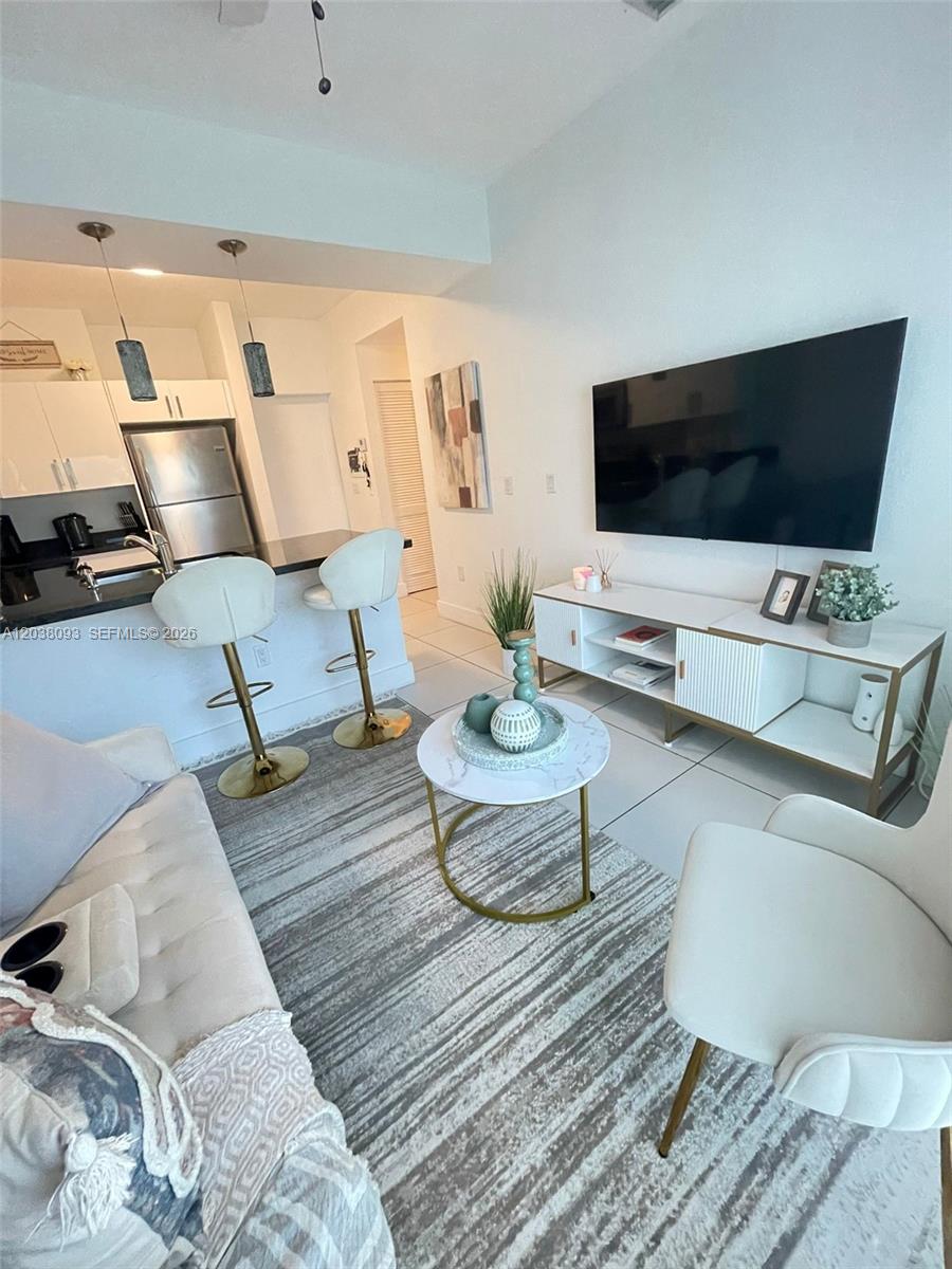 A living room features a white sofa, a marble coffee table, and a kitchen area — 106 SE 9th Ct # 201, Hallandale Beach FL 33009, HALLANDALE BEACH, FL